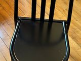 une chaise noire posée sur un parquet dans un salon