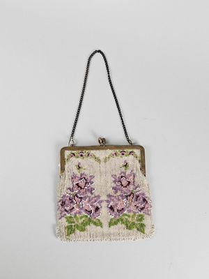 un sac à main blanc orné de fleurs violettes, suspendu à une chaîne