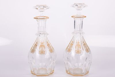 deux bouteilles en verre transparent ornées de motifs dorés