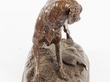 bronze statue of a dog on a rock on a white background
