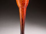 an orange vase sitting on top of a white table next to a black wall