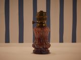 a pink glass bottle with a gold top on a table