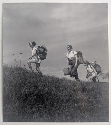 photographie en noir et blanc d'un groupe de personnes munies de sacs à dos qui montent en courant une colline