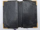 an open black leather book sitting on top of a white table