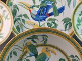 four plates with birds painted on them sitting on a table