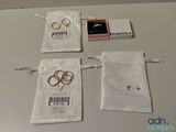 trois alliances sont posées sur un sac en tissu blanc, à côté d'une bague rose
