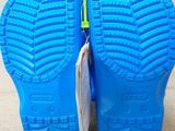 pair of children ' s blue rubber shoes with green soles