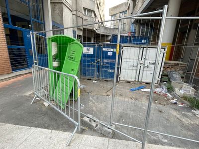 une chaise verte derrière une grille métallique sur le trottoir