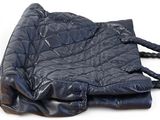a black quilted bag sitting on top of a white surface