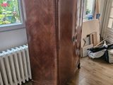 a wooden cabinet in the corner of a room with a radiator in the corner