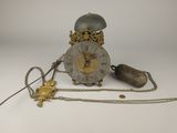 une horloge entourée d'une chaîne, posée sur une surface blanche