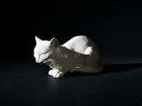 une figurine de chat blanc posée sur une surface noire