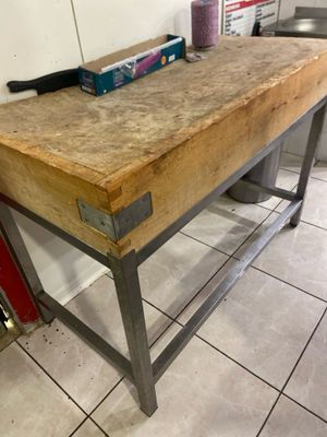 une table en bois sur laquelle est posé un couteau, dans une cuisine
