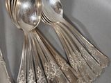 a lot of silver spoons and spoons sitting on a table