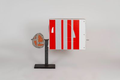 a red and white sign on a stand with a fan