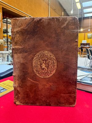 an old book sitting on top of a table next to a red table cloth