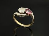 un gros plan d'une bague en or sertie d'une pierre rose et blanche