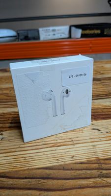 a white box on a wooden table with an apple airpods on it
