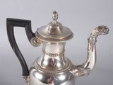 a silver tea pot with a black handle on a table