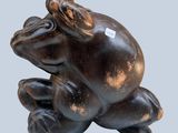 statue of a frog sitting on its back on a gray background