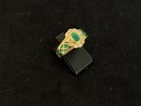 an image of a gold ring with green stones on a black surface