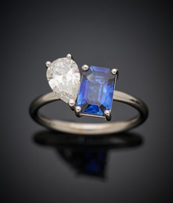 un gros plan d'une bague sertie d'un diamant et d'un saphir sur une surface noire