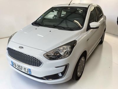 the white car is parked in a white room with a man standing next to it