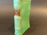 an old book sitting on top of a table covered in green cloth