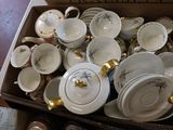 a box full of white and gold china plates and bowls