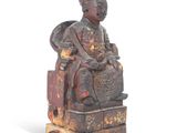 statue d'un homme assis sur une chaise, coiffé d'un chapeau