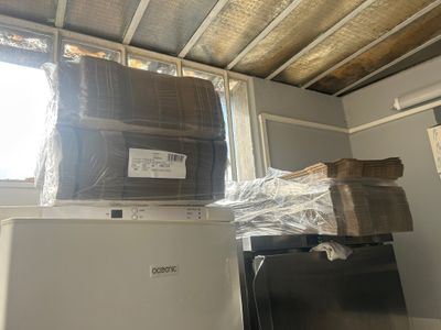 un réfrigérateur et un congélateur dans une pièce où il y a beaucoup de cartons posés dessus