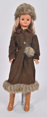 une poupée qui porte un manteau marron et des bottes
