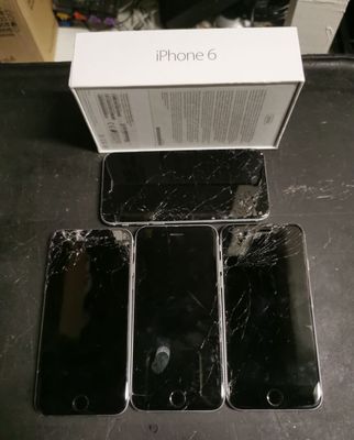 three black iphones are sitting on a table with a box in front of them