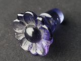 a purple glass flower with a black center on a black surface