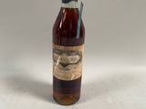 une vieille bouteille de whisky posée sur une table blanche