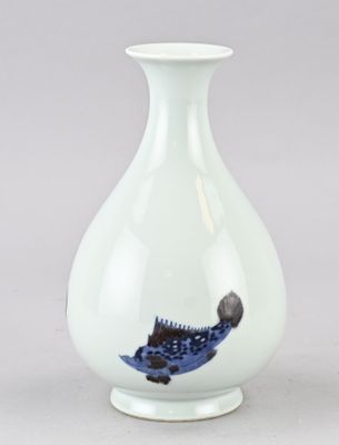 un vase blanc orné d'un motif de poisson bleu