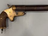 un gros plan d'un revolver à crosse en bois accroché au mur