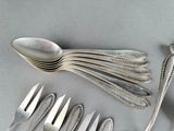 a lot of silver spoons and forks laid out on a table