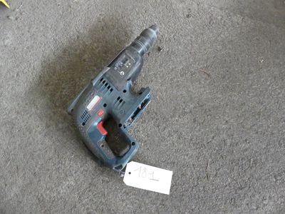 a corded drill on the floor next to a piece of paper
