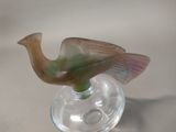a glass bird that is sitting on top of a wine glass