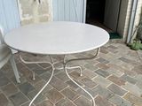 une table blanche et deux chaises sur une terrasse en pierre