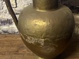 un vase en or posé sur une table en bois, avec une étiquette