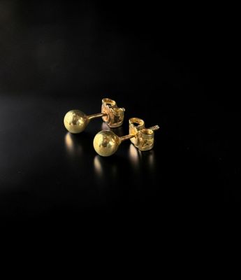 a pair of gold stud earrings on a black surface