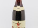 une vieille bouteille de vin rouge posée sur une table blanche