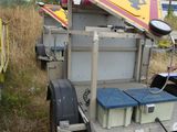 a small trailer with a trailer attached to it in the grass