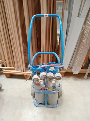 un chariot bleu sur lequel sont posés trois cylindres, dans une pièce
