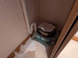 des toilettes situées dans un coin d'une salle de bains, avec un rouleau de papier toilette posé par terre