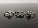 trois bagues de fiançailles ornées de diamants posées sur une surface noire