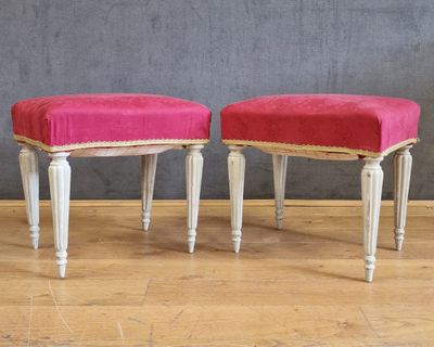 une paire de tabourets rembourrés roses aux pieds blancs, posés sur un parquet