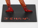 a figurine of a man in red shoes on a black base